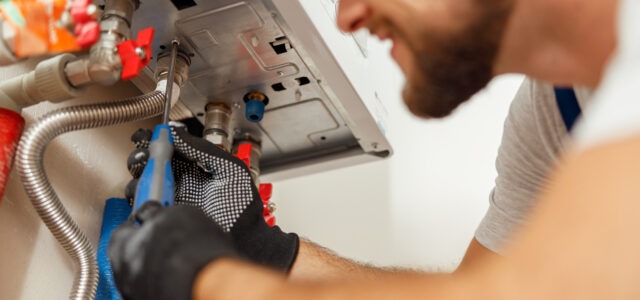 Closeup of plumber using screwdriver while installing new steel hot water central heating system in apartment. Manual work, maintenance, repair service concept